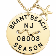 Load image into Gallery viewer, A gold round beach tag pendant necklace engraved with 'BRANT BEACH NJ 08008 SEASON' and a starfish charm, shown on a white background.