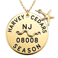 Load image into Gallery viewer, A gold-toned round beach tag pendant necklace engraved with 'HARVEY CEDARS NJ 08008 SEASON' and a wavy line motif, shown on a chain with a small starfish charm against a white background.