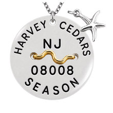 Load image into Gallery viewer, A silver round beach tag pendant necklace with a starfish charm and a gold wavy accent, featuring the text 'HARVEY CEDARS', 'NJ', '08008', and 'SEASON' on a white background.