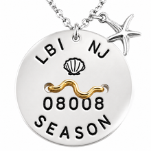 Load image into Gallery viewer, A silver round beach tag pendant necklace on a chain, featuring a starfish charm. The pendant is engraved with 'LBI NJ', a seashell, the number '08008', and 'SEASON' in black, with a wavy gold accent across the center.