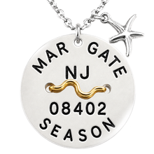 Load image into Gallery viewer, A silver-toned round beach tag pendant necklace with a starfish charm, featuring black engraved text reading 'MARGATE NJ 08402 SEASON' and a wavy gold accent across the center, shown on a white background.