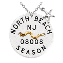 Load image into Gallery viewer, A silver round Beach Tag pendant necklace engraved with 'NORTH BEACH NJ 08008 SEASON' and a wavy gold accent, featuring a silver starfish charm on a white background.