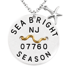 Load image into Gallery viewer, A sterling silver round beach tag pendant necklace engraved with 'SEA BRIGHT NJ 07760 SEASON' and a gold wavy line detail, featuring a dangling silver starfish charm on a white background.