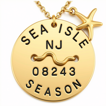 Load image into Gallery viewer, A gold-toned round beach tag pendant necklace engraved with 'SEA ISLE NJ 08243 SEASON' and a wavy line, featuring a starfish charm and chain on a white background.