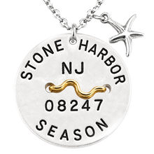 Load image into Gallery viewer, A sterling silver round beach tag pendant necklace engraved with 'STONE HARBOR NJ 08247 SEASON' and a gold wavy accent, featuring a dangling silver starfish charm on a white background.
