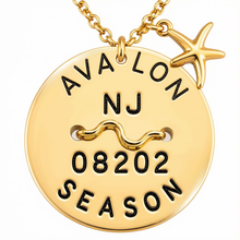 Load image into Gallery viewer, A gold round beach tag pendant necklace engraved with 'AVA LON NJ 08202 SEASON' and a wavy line symbol, featuring a small gold starfish charm, on a white background.
