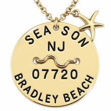 Load image into Gallery viewer, A gold-toned round beach tag pendant necklace engraved with 'SEA SON NJ 07720 BRADLEY BEACH' and a wavy line motif, featuring a small starfish charm on a matching chain against a white background.
