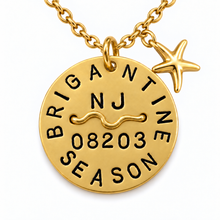 Load image into Gallery viewer, A gold-toned round beach tag pendant necklace engraved with 'BRIGANTINE SEASON' and 'NJ 08203' with a zodiac symbol, hanging from a gold chain with a small starfish charm, on a white background.
