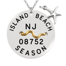 Load image into Gallery viewer, A silver round beach tag pendant necklace with a starfish charm, featuring a gold wavy accent and black engraved text reading 'ISLAND BEACH', 'NJ', '08752', and 'SEASON'.
