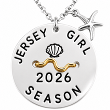 Load image into Gallery viewer, A silver round beach tag pendant necklace on a chain, featuring a starfish charm and a gold wave accent. The pendant is engraved with 'JERSEY GIRL 2026 SEASON' and a seashell icon, shown on a plain white background.
