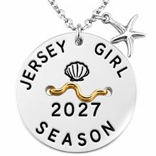 Load image into Gallery viewer, A silver round beach tag pendant necklace engraved with 'JERSEY GIRL 2027 SEASON' and a seashell motif, featuring a gold wavy accent and a small silver starfish charm, shown on a white background.
