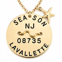 Load image into Gallery viewer, A gold personalized beach tag pendant necklace featuring a round disc engraved with 'SEASON NJ 08735 LAVALLETTTE' and a wavy line symbol, accompanied by a starfish charm on a white background.
