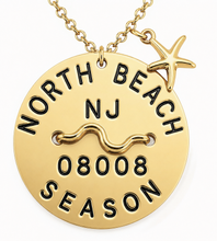 Load image into Gallery viewer, A gold round beach tag pendant necklace engraved with 'NORTH BEACH NJ 08008 SEASON' and a wavy line symbol, featuring a small gold starfish charm, on a white background.
