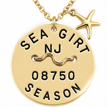 Load image into Gallery viewer, A gold-toned round beach tag pendant necklace with a starfish charm, featuring the text 'SEA GIRT NJ 08750 SEASON' and a wavy line motif on a white background.
